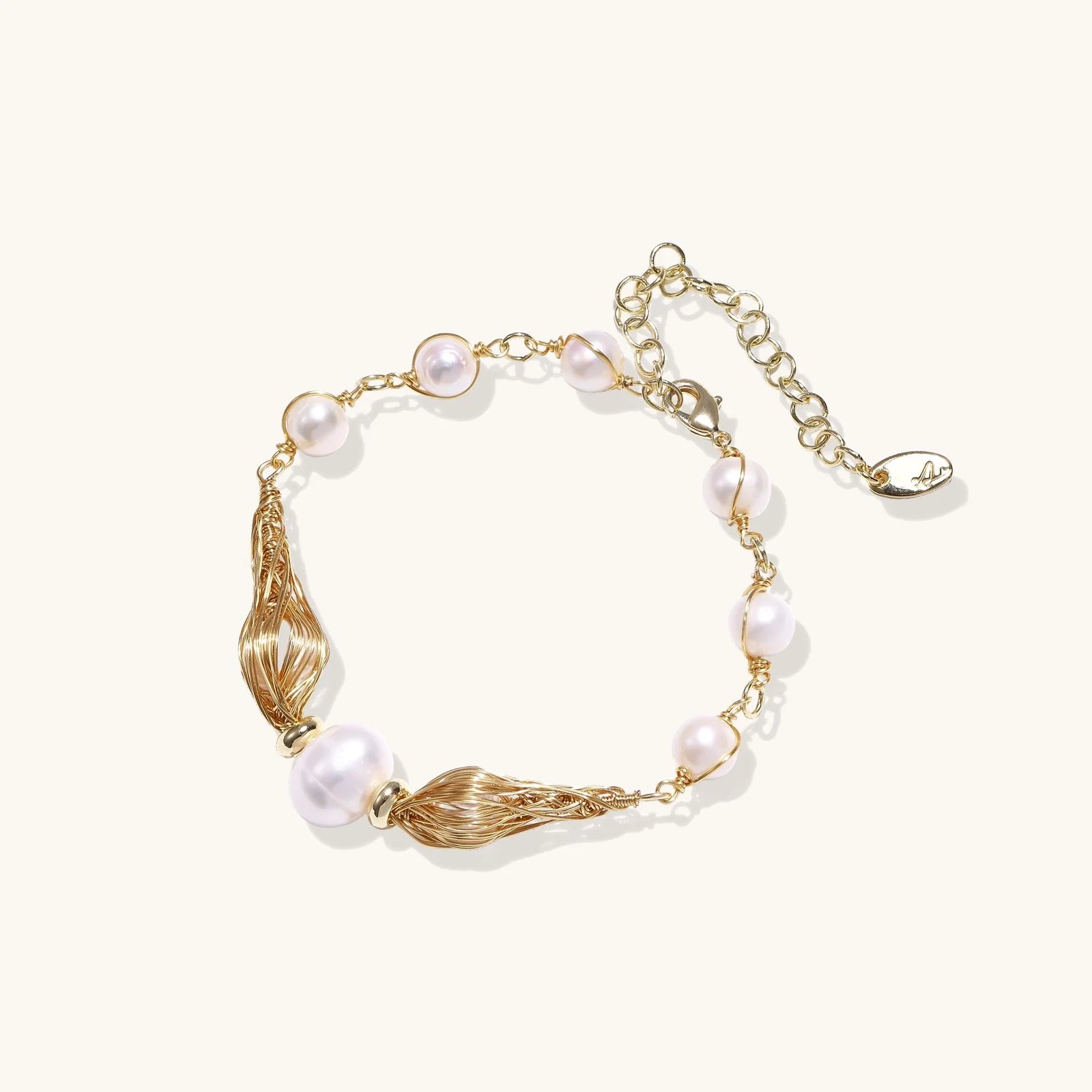 Adjustable gold bracelet with freshwater pearls and textured filigree beads on white background, showing clasp detail.