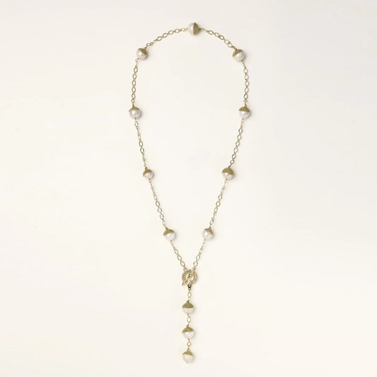 Gold-plated lariat necklace with baroque pearls and textured caps on cream background, showing adjustable Y-shaped design.