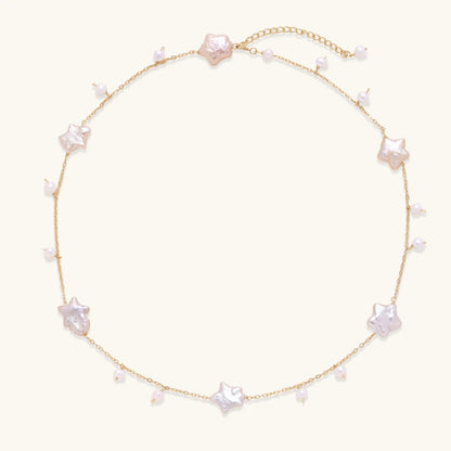 Gold vermeil chain with iridescent star-shaped baroque pearls and small round freshwater pearl drops on cream background.