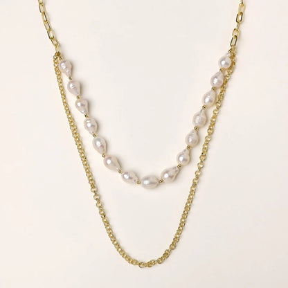 Layered gold chain necklace with organic baroque freshwater pearls and adjustable length on cream background