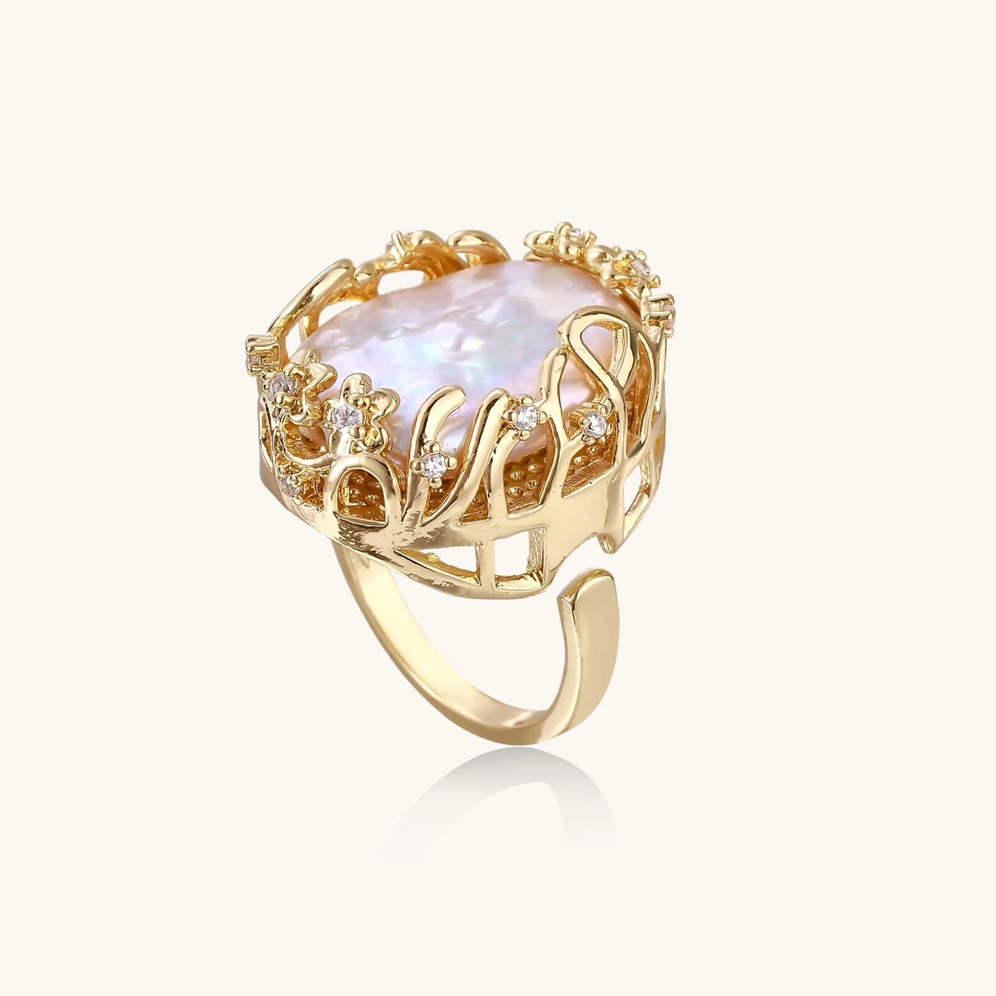 Gold filigree crown ring cradling an iridescent baroque freshwater pearl with crystal accents on white background