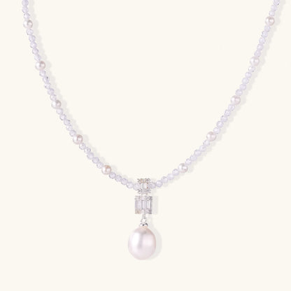 Dainty necklace with lavender crystal beads, freshwater pearls, geometric pendant, and large pearl drop on white background.