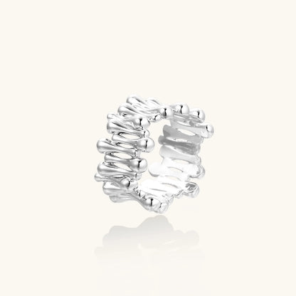 Wide band ring with sculptural wave ripples in polished white gold plated eco-brass on cream background