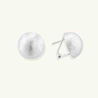 Brushed sterling silver half-dome clip-on earrings with textured surface against cream background