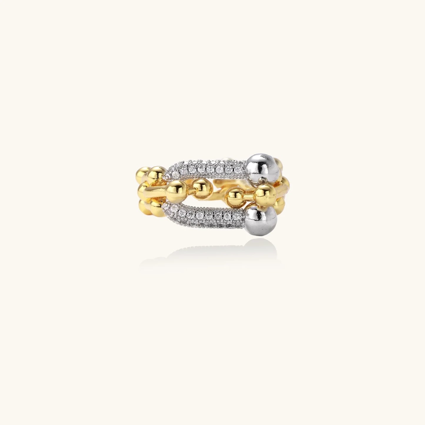 Triple-band gold ring with spherical bead chains and two crystal-pavé bars on cream background