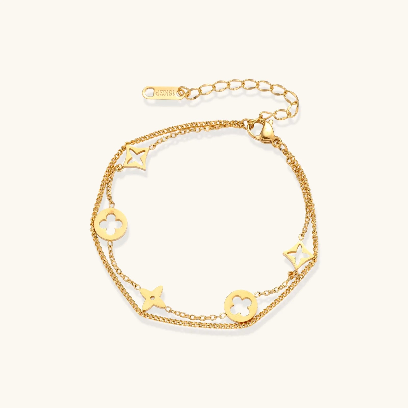 Double-layer gold-plated bracelet with quatrefoil and star charms on cream background, 18K gold finish.