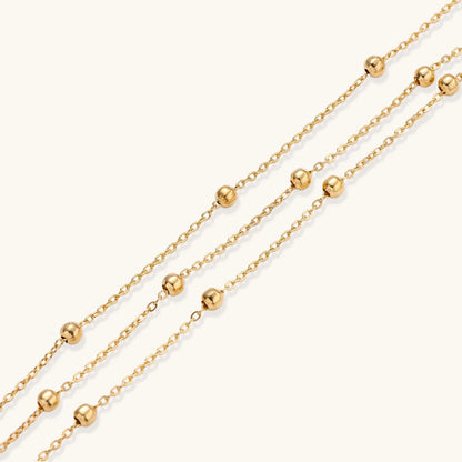 Three-strand gold-plated bracelet with clustered ball beads and adjustable clasp on cream background