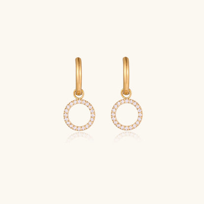 Gold-plated huggie hoop earrings with CZ-studded open circle charms on beige background