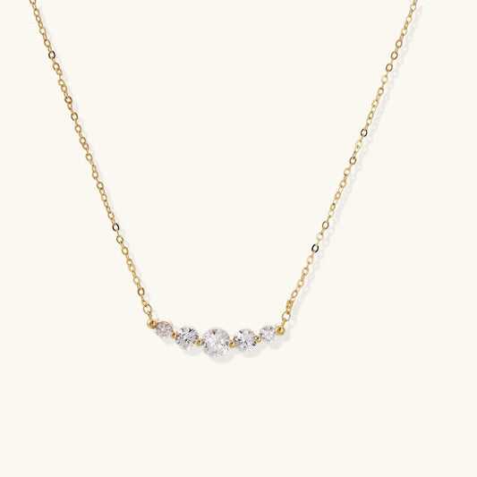 Delicate 14K gold-plated necklace with five graduated zirconia stones arranged in a curved arc on fine chain