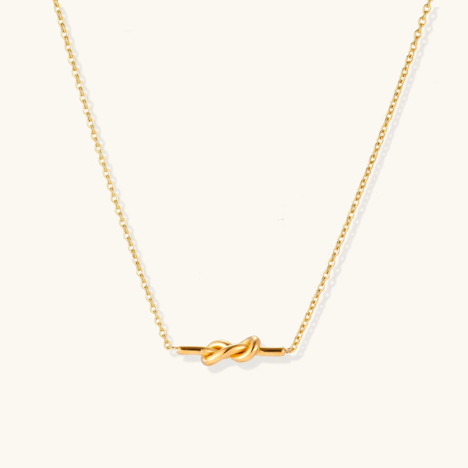 Dainty 18K gold plated necklace with infinity knot pendant on delicate chain against white background