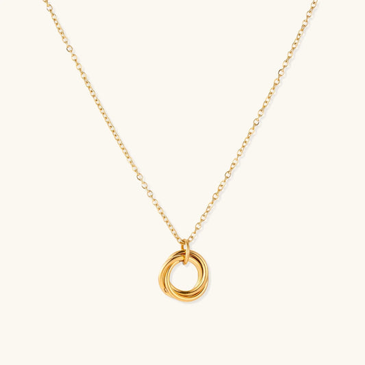 Delicate gold-plated necklace with three interlocking circle rings forming a minimalist knot pendant on cream background
