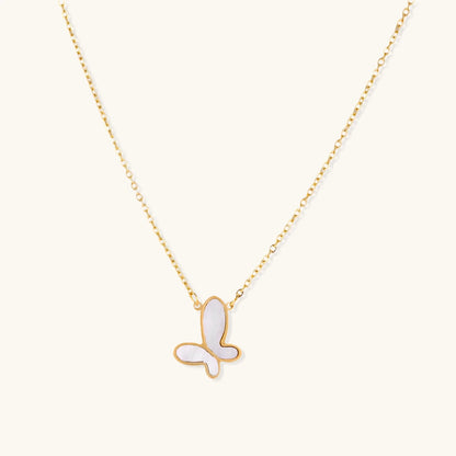 Gold-plated butterfly pendant with iridescent mother of pearl inlay on delicate chain against cream background.